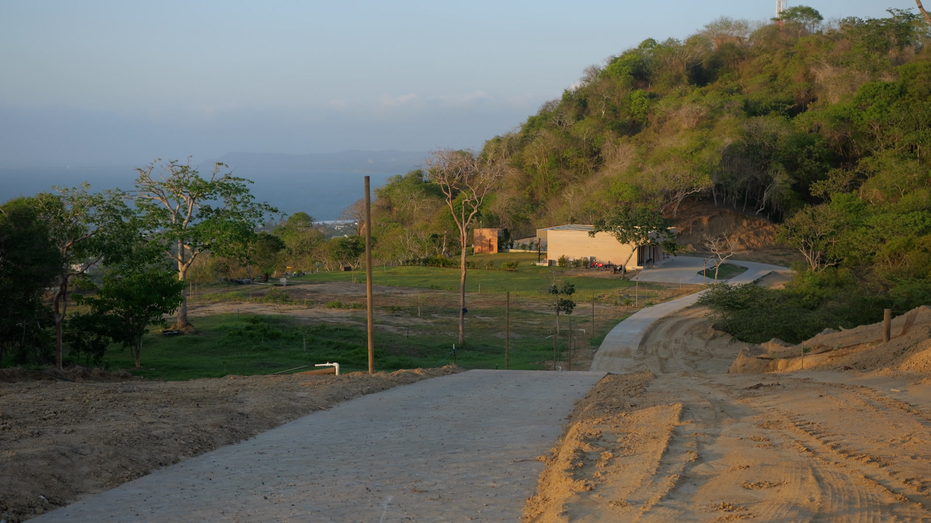 Vía interna del proyecto al atardecer con vista al mar