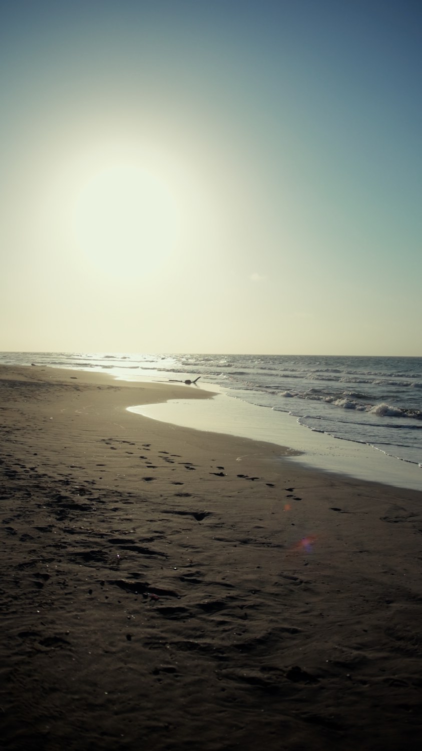 La orilla de la playa al atardecer, con el sol bajo sobre el Caribe